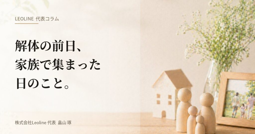 畠山琢の代表コラム『解体の前日、家族で集まった日のこと。』のアイキャッチ画像。木製の家族フィギュアと家のミニチュア、写真立てが並ぶ静謐なテーブル。